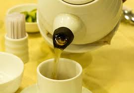 white ceeramic tea pot pouring tea into white cup on yellow tablecloth